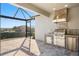 Covered outdoor kitchen featuring a stainless grill, sink and refrigerator at 970 Timberview Rd, Clermont, FL 34715