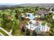 Aerial view of resort-style pool and splash pad area with lounge, surrounded by lush landscaping and palm trees at 970 Timberview Rd, Clermont, FL 34715