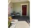 Charming front porch with a welcoming red door, seating and beautiful plants at 9978 Tivoli Villa Dr, Orlando, FL 32829