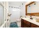 Vintage bathroom features tile flooring, wood vanity, gold mirror, and a shower with white curtain at 10423 Manassas Cir, Orlando, FL 32821