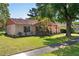 Well-maintained home with a red tile roof, lush green lawn, and mature trees at 10423 Manassas Cir, Orlando, FL 32821
