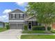 Charming two-story gray home featuring a two-car garage, lush landscaping, and a welcoming front entrance at 10435 Eastpark Lake Dr, Orlando, FL 32832