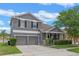Two-story gray home with a two-car garage, mature trees, and well-maintained landscaping at 10435 Eastpark Lake Dr, Orlando, FL 32832