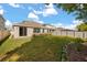 Well-maintained backyard with a lush lawn, white fence, and a covered patio sliding glass doors at 1109 Castlevecchio Loop, Orlando, FL 32825