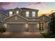 Charming two-story home with a brick driveway and a well-manicured lawn at sunset at 1109 Castlevecchio Loop, Orlando, FL 32825