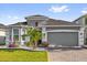 Charming gray home featuring manicured lawn, beautiful landscaping, brick driveway, and two-car garage at 1210 Pando Loop, Orlando, FL 32824