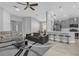 Open-concept living room and kitchen featuring modern furniture, ceiling fan, and breakfast bar at 1210 Pando Loop, Orlando, FL 32824