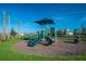 Community playground with green slides, and palm trees against a clear blue sky at 1210 Pando Loop, Orlando, FL 32824