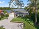 Single-story home boasts a paver driveway, a lush lawn, a basketball court, and lake views at 1322 Palm Dr, Apopka, FL 32703