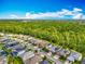 Aerial view showcases the community's modern homes, solar panels, and green spaces against a backdrop of distant wooded areas at 14001 Jomatt Loop, Winter Garden, FL 34787