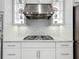 Close up view of a gas cooktop and stainless range hood with open shelving at 14001 Jomatt Loop, Winter Garden, FL 34787