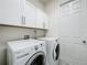 Laundry room with white cabinets above a Whirlpool washer and dryer, and a door to the side at 14001 Jomatt Loop, Winter Garden, FL 34787