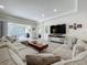 Modern living room with a large sectional sofa, mounted TV, and a seamless transition to the outdoor space at 14001 Jomatt Loop, Winter Garden, FL 34787