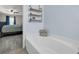 Bathroom featuring a bathtub, gray laminate floors, three-tier wall mounted display shelving, and light blue walls at 145 Circle Hill Rd, Sanford, FL 32773