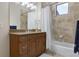 Bathroom featuring a bathtub with shower, tile surround and a wood vanity with granite countertop at 14700 Avenue Of The Rushes, Winter Garden, FL 34787