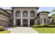 Close-up of a two-story home featuring arched entryways, manicured landscaping, and a brick driveway at 14700 Avenue Of The Rushes, Winter Garden, FL 34787