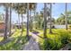 Lush backyard with a stone path, mature palms, fire pit, and well-maintained lawn at 1617 Hontoon Rd, Deland, FL 32720
