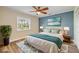 Bright bedroom with a ceiling fan, white bedspread, blue accent wall, and a window with a view of the outside landscape at 1617 Hontoon Rd, Deland, FL 32720