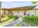 Home exterior showcasing a covered patio, stone walkway, garden, and well-manicured lawn at 1617 Hontoon Rd, Deland, FL 32720