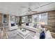 Sunroom-style living room featuring a white sofa and chairs, wood paneling, and large windows at 1617 Hontoon Rd, Deland, FL 32720