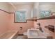 Retro bathroom featuring classic pink tiling and fixtures around the bathtub, sink, and window at 1821 Goodrich Ave, Winter Park, FL 32789