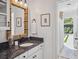 Bright bathroom featuring a decorative mirror, white cabinets, dark countertops, and a view of the backyard at 2004 Mohawk Trl, Maitland, FL 32751