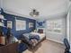 This well-lit bedroom features blue accent walls, a ceiling fan, and two windows with shutters at 2004 Mohawk Trl, Maitland, FL 32751