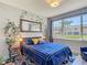 Cozy bedroom featuring a blue bed, a large window with a view, and vine-covered mirror decor at 2012 Gold Spring Cv, Kissimmee, FL 34743