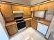 Functional kitchen with wooden cabinets, white appliances, and white tile flooring at 2348 Sun Valley Cir, Winter Park, FL 32792