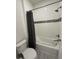 Clean white bathtub and shower combination with decorative tile, white toilet and gray tiled flooring at 2741 Nottel Dr, St Cloud, FL 34772