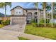Elegant two-story home with mature landscaping, paver driveway, and a two-car garage under a blue sky at 305 Kays Landing Dr, Sanford, FL 32771