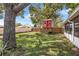 Lush backyard with a unique red treehouse, surrounded by mature trees and green grass at 3205 Clewiston St, Deltona, FL 32738