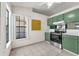 Sunlit kitchen featuring stainless steel appliances, green cabinetry, and tile flooring at 3205 Clewiston St, Deltona, FL 32738