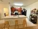 Cozy kitchen with a granite countertop island, barstool seating, wooden cabinets, and modern black appliances at 3702 Maidencain St, Clermont, FL 34714