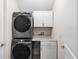 Efficient laundry room with stacked washer and dryer, plus storage cabinets and counter at 416 Southfield St, Kissimmee, FL 34747