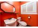 Bright orange bathroom featuring a white sink, toilet, and window at 420 N Center St, Eustis, FL 32726