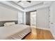 Well-lit primary bedroom boasts a tray ceiling, hardwood floors, and a barn door to the en-suite bathroom at 441 N Capen Ave, Winter Park, FL 32789