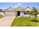 Well-maintained single-Gathering home featuring manicured lawn, gray exterior, attached garage, and classic architectural details at 445 Auburn Grove Pl, Auburndale, FL 33823