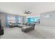 Spacious living room with large windows, comfortable gray sectional sofa, ceiling fan, and views into the kitchen at 445 Auburn Grove Pl, Auburndale, FL 33823