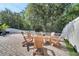 Backyard firepit and seating area with brick pavers, lush trees, and a white picket fence at 460 Crownclover Ave, Orlando, FL 32828