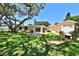Beautiful backyard with lush grass, patio seating, mature trees and a charming exterior at 505 S Cooper St, New Smyrna Beach, FL 32169