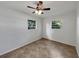 This bedroom features two windows, a ceiling fan and neutral walls with tile flooring at 5939 Stokes Rd, Lakeland, FL 33812