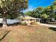 Charming single-story home with a vibrant yellow exterior, lush greenery and a white fence at 5939 Stokes Rd, Lakeland, FL 33812