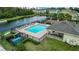 Aerial view of a community pool area, featuring a covered patio, lake, and playground at 6863 Tussilago Way, Orlando, FL 32822