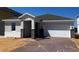 Charming one-story home with brick-paved driveway, gray roof, and stone-accented columns at 7138 Rolling Leaf Rd, Groveland, FL 34736