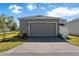 A detached, modern two car garage with a brick paver driveway and well manicured lawn at 779 Firerock Ln, Debary, FL 32713