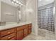 Well-lit bathroom featuring a vanity with a large mirror, wood cabinets and a shower with patterned curtain at 9018 Southern Breeze Dr, Orlando, FL 32836