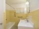 Bright bathroom with a tub, tiled yellow walls, and a white sink at 1125 N Mc Donald St, Mount Dora, FL 32757