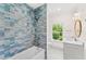 Bright bathroom with blue-tiled shower and bathtub, window, and vanity at 1341 Lyndale Blvd, Winter Park, FL 32789
