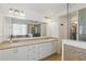 Bright bathroom with double sinks, a large mirror, shower with glass doors, and ample natural light at 14838 Bahama Swallow Blvd, Winter Garden, FL 34787